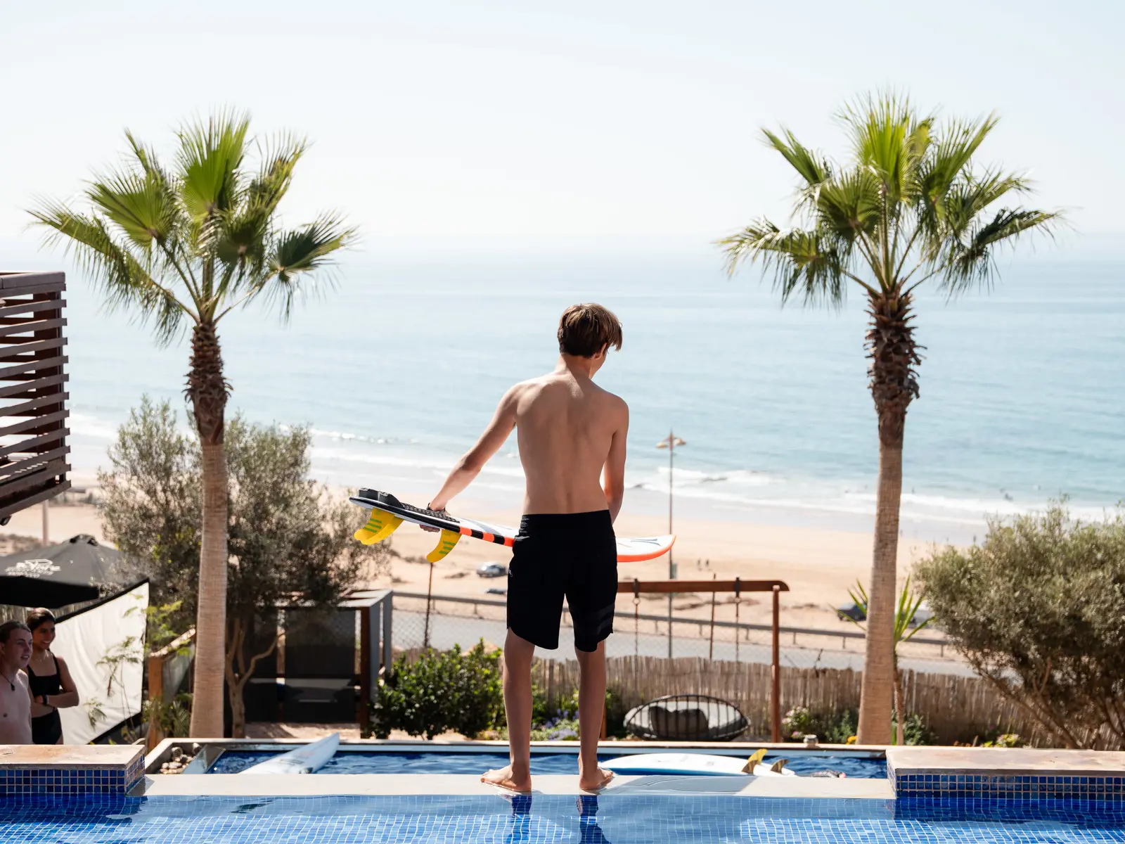 Surfer by pool overlooking the beach in Morocco