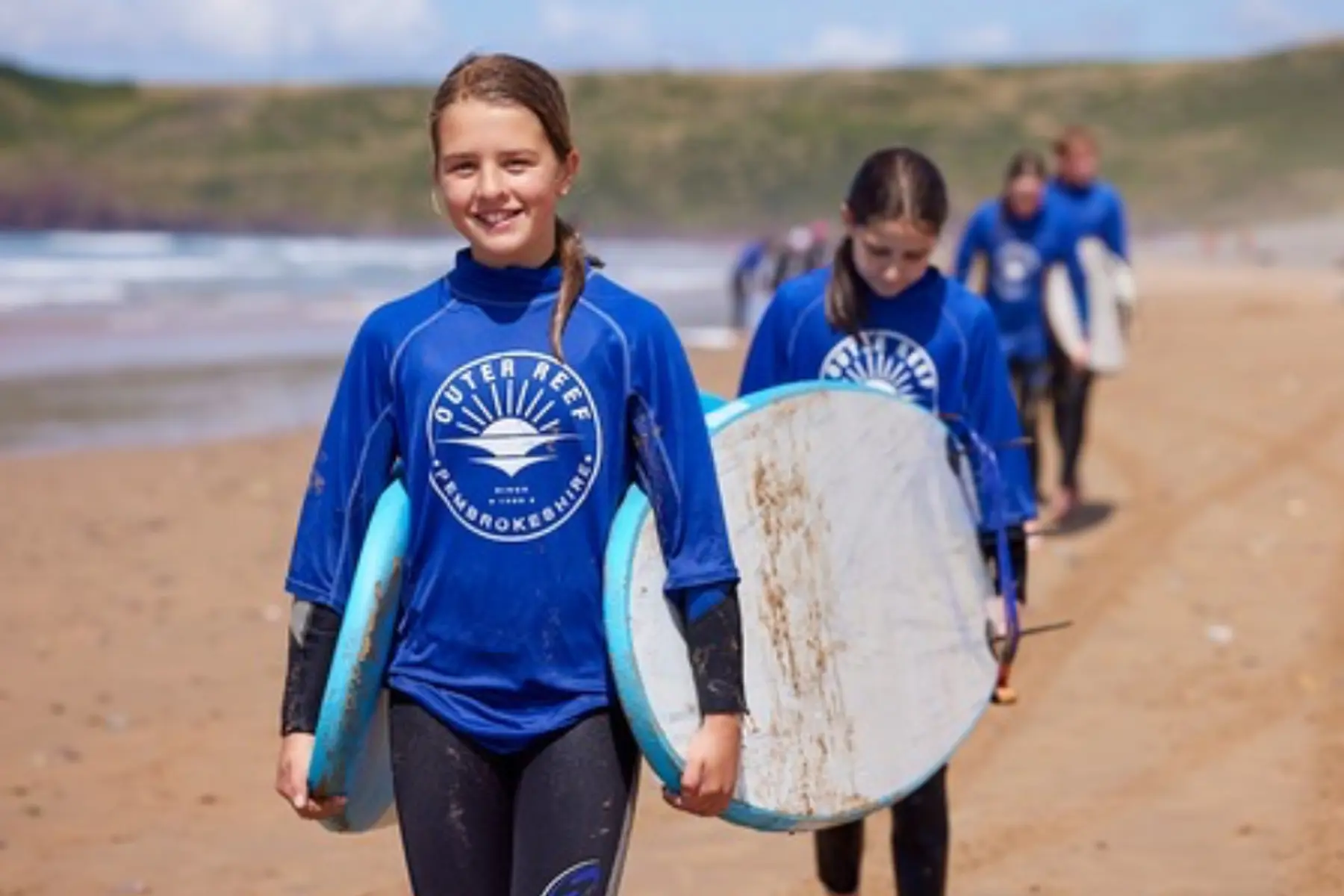 Beginner surfer catching a wave during an Outer Reef surf lesson in Pembrokeshire Wales